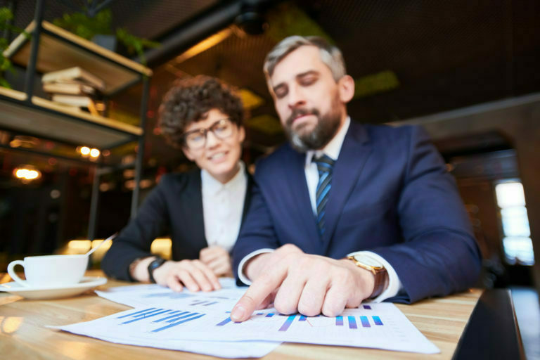 a man and woman sitting at a table with papers and a book