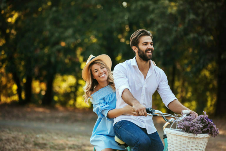 a person and a girl sitting on a bench with a basket of grapes