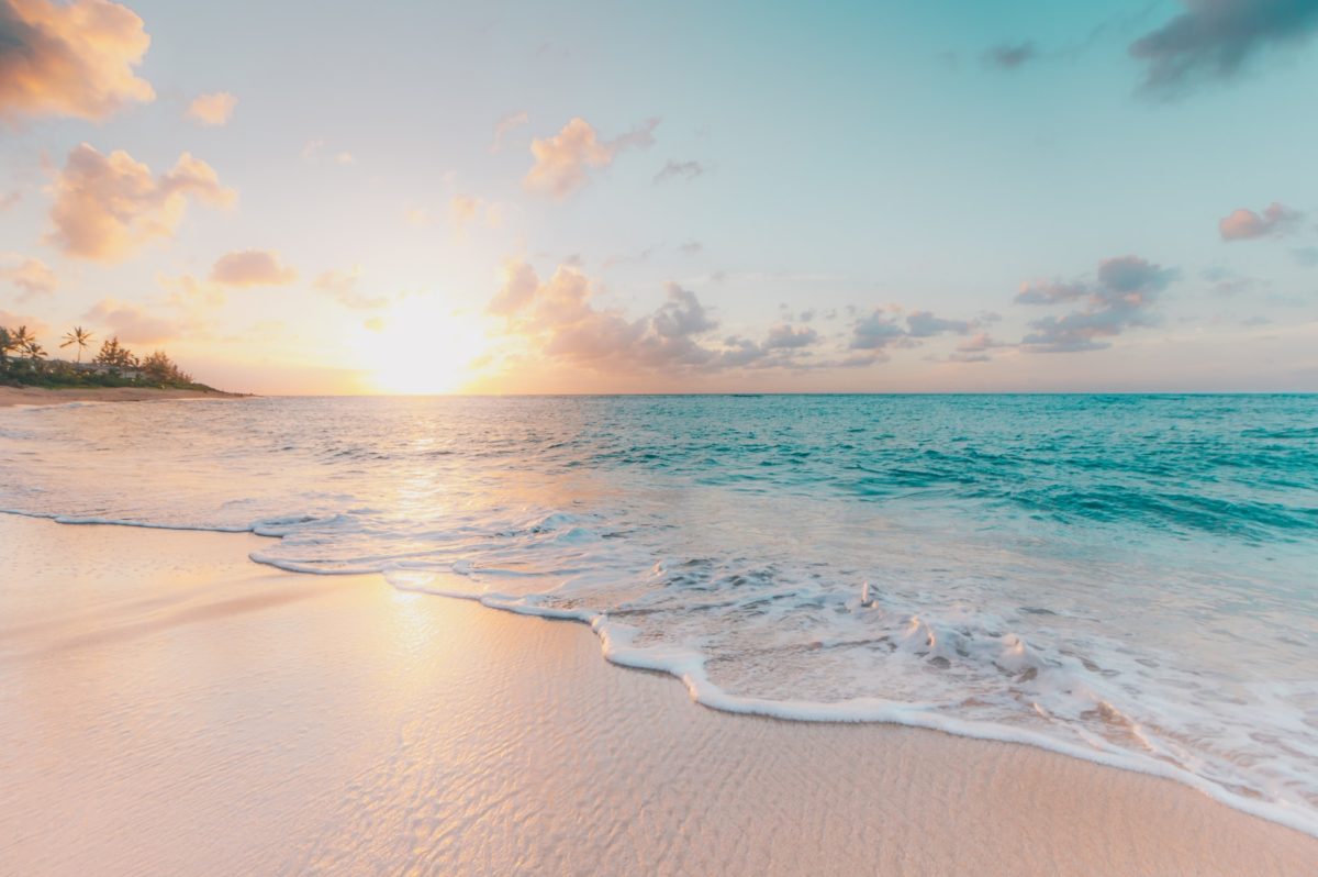 a beach with the sun setting