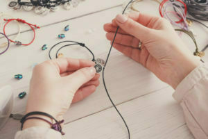 a person's hands holding a wire over a white surface